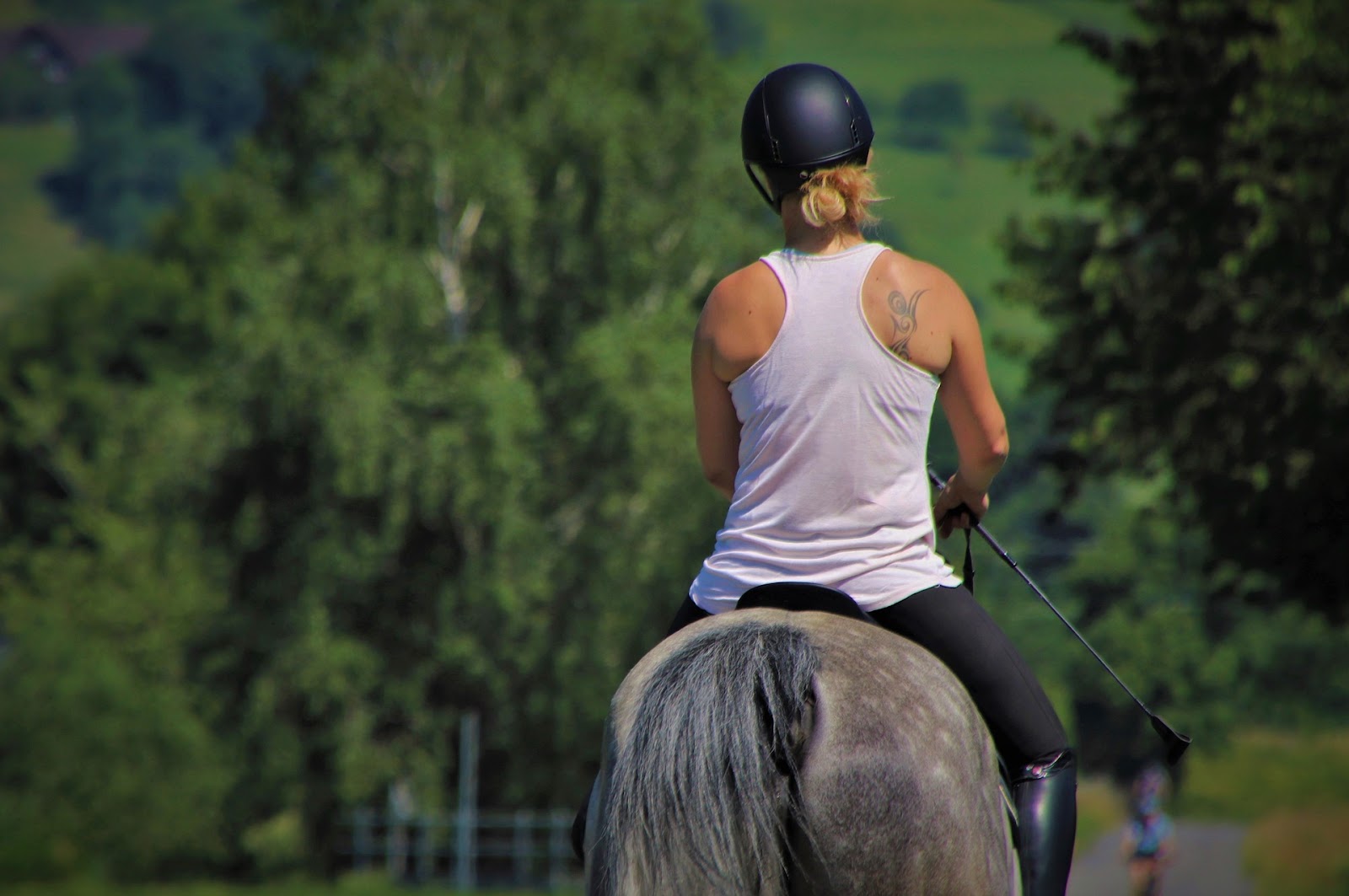 woman wearing helmet rides a grey horse