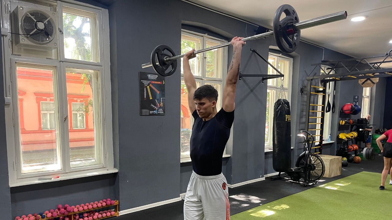 Vanja performs the barbell overhead press exercise.