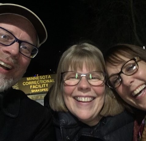 a man and two women leaning their heads together and laughing 