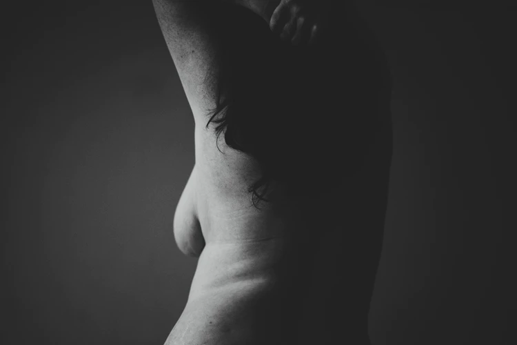 Black and white shot of a woman, expressively showing her side breast
