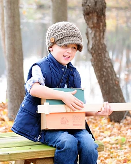 boy outside wearing a brown newsboy hat with buttons