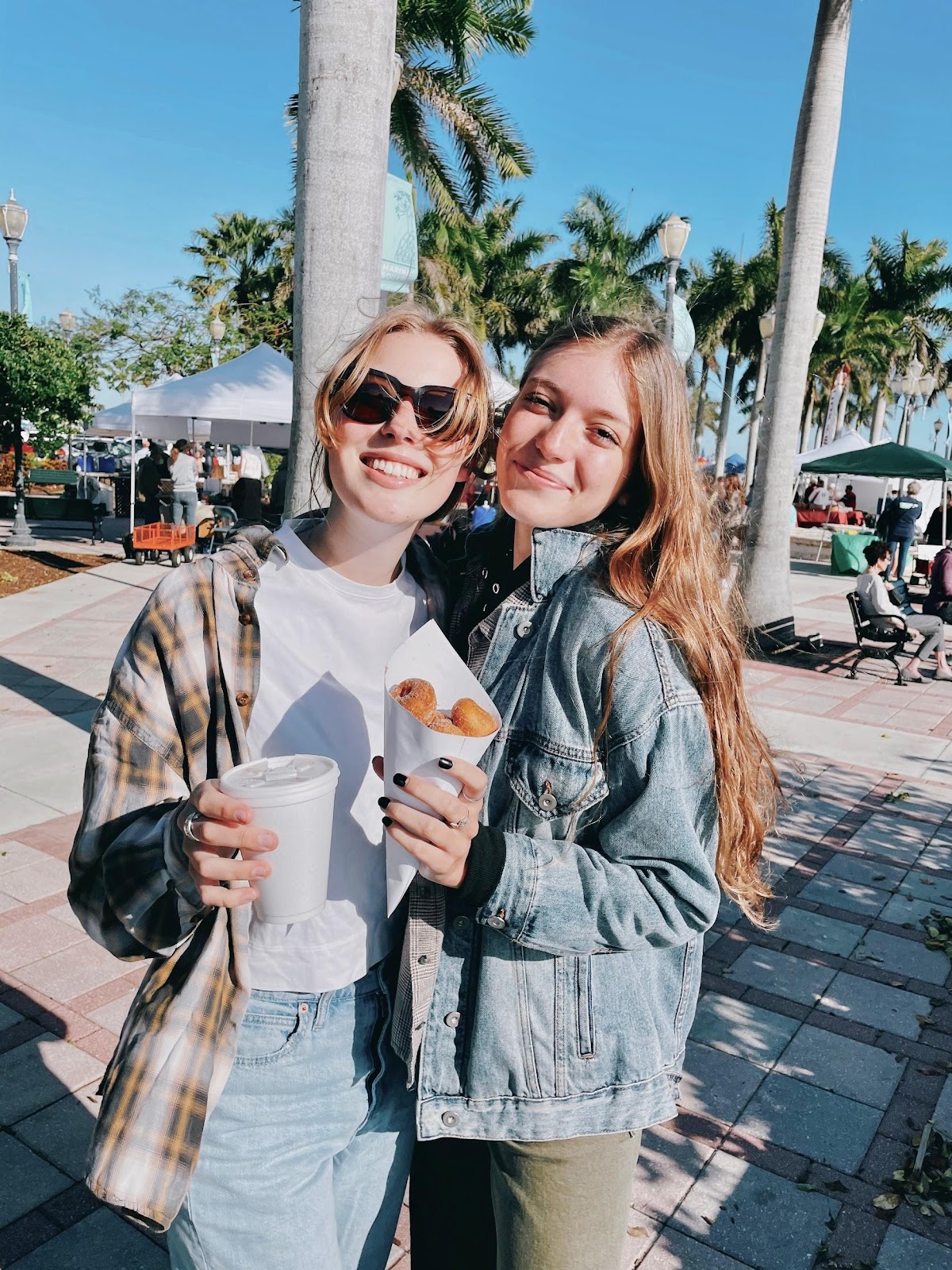 Ellie and Nina smiling from a beach with some street food