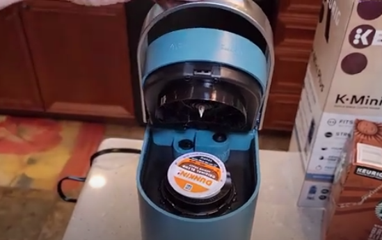 
This image provides instructions on "Re-Inserting the Pod" for the article "Keurig K-Mini Plus Problems: Why Are My Keurig K-Mini Plus Flashing Lights?