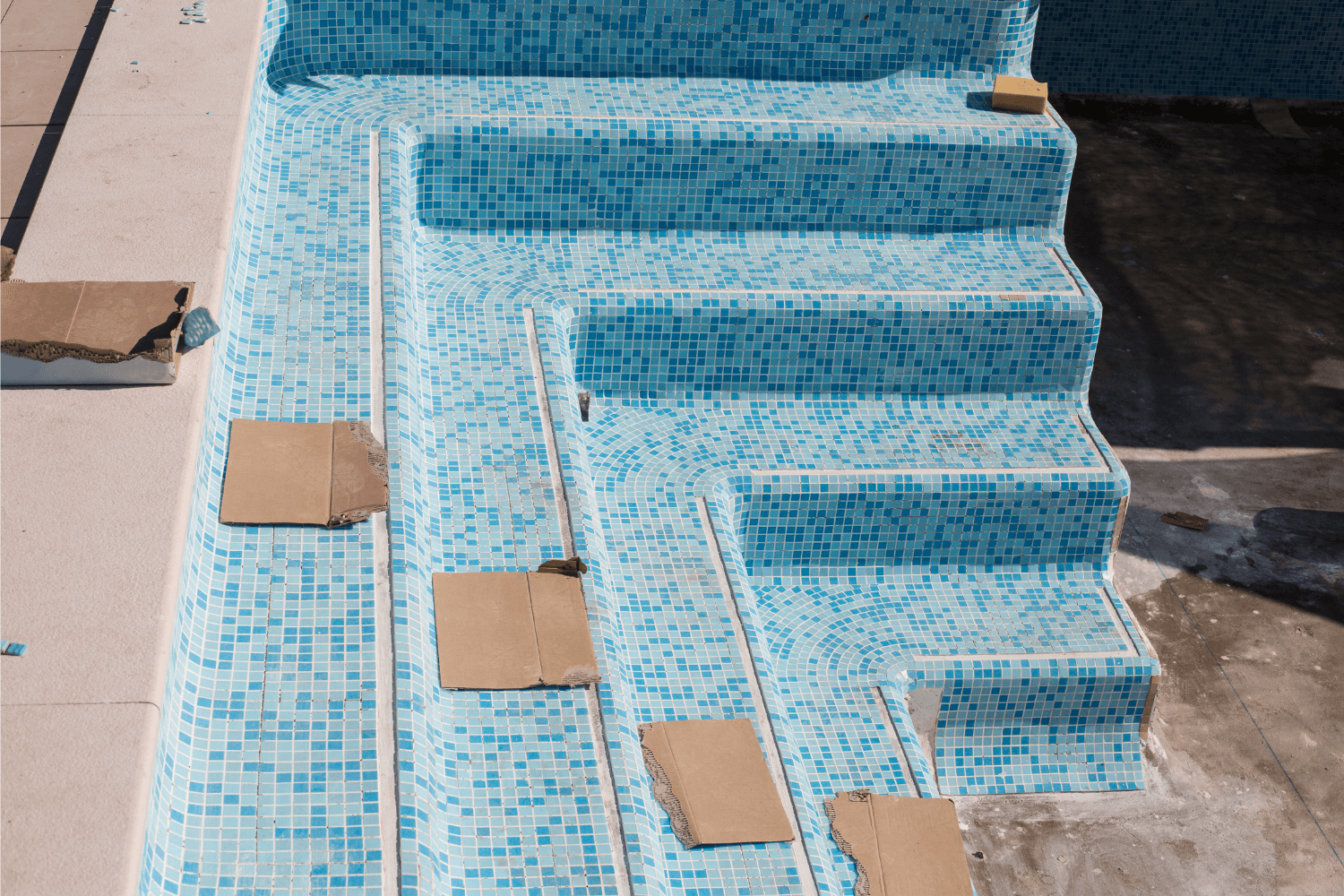 Residential swimming pool steps getting new tiles installed