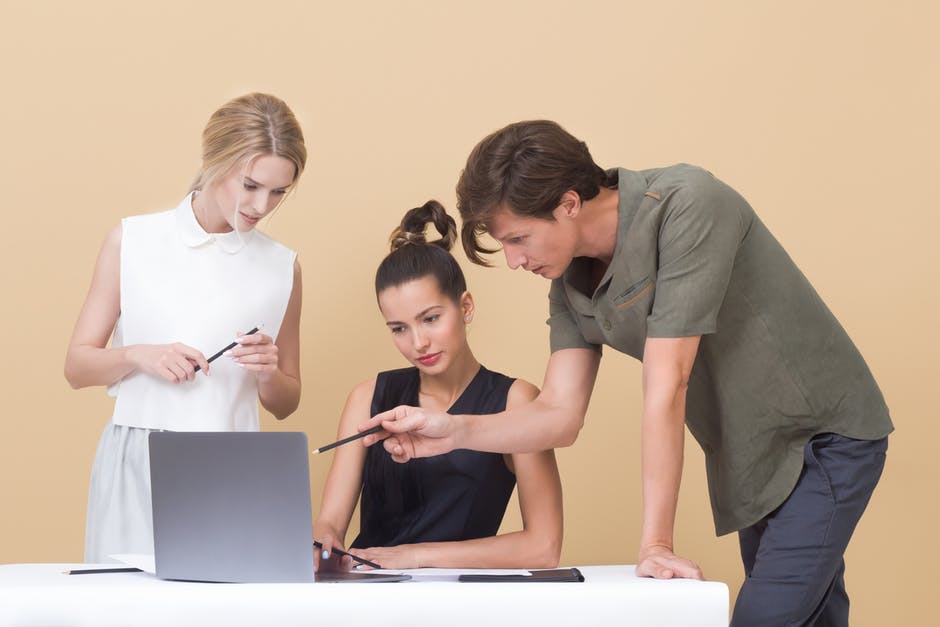 two women and a man looking at a computer screen and discussing work abroad job opportunities