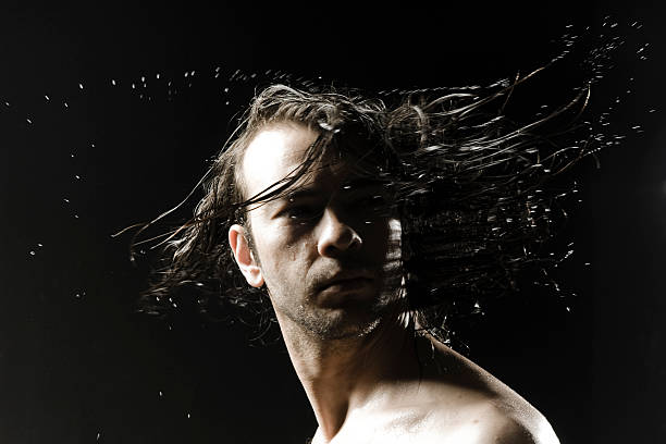 Closeup shot of a long haired man with wet hair in dark backgorund