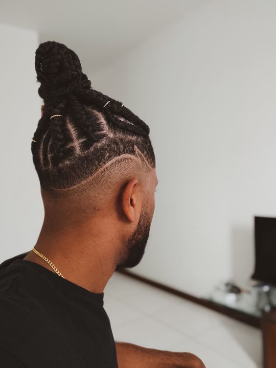 a guy wearing braided man bun with fades