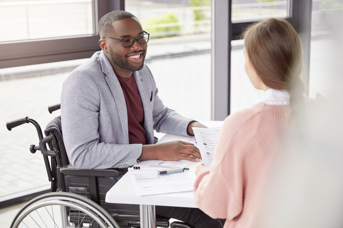ADA interactive process: employee sitting in a wheelchair while talking to his colleague
