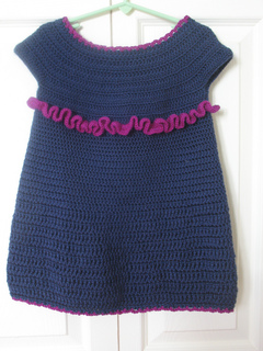 crochet toddler dress hanging on hanger