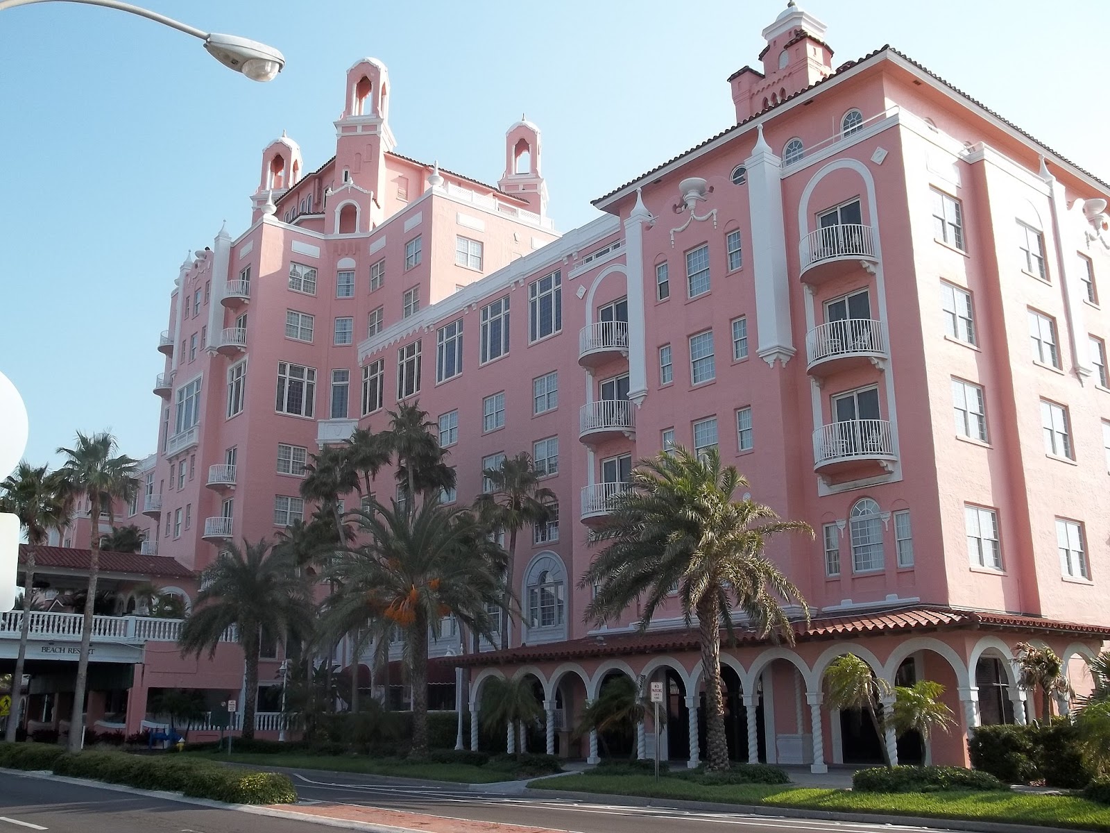 Large pink and white building lined with palm trees on St. Pete beach 