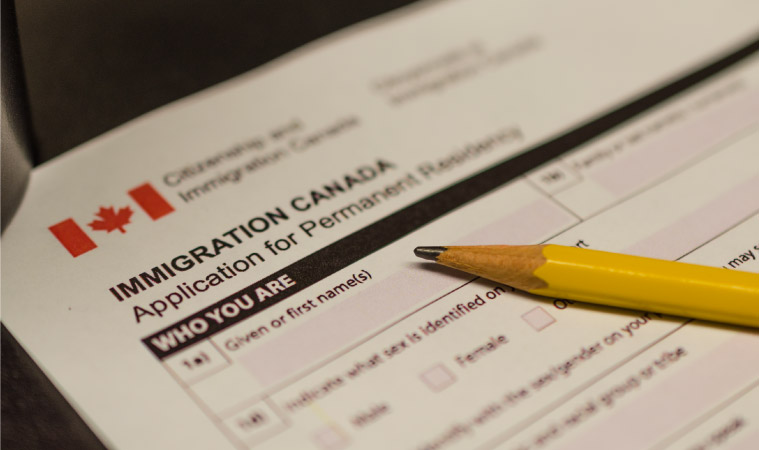 A close-up view of an immigration form for people who are applying for permanent residency in Canada. There’s a pencil resting on top of the form.