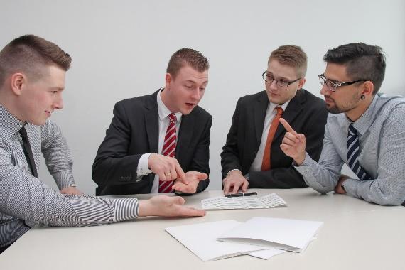 A group of men sitting at a table looking at papers

Description automatically generated with medium confidence