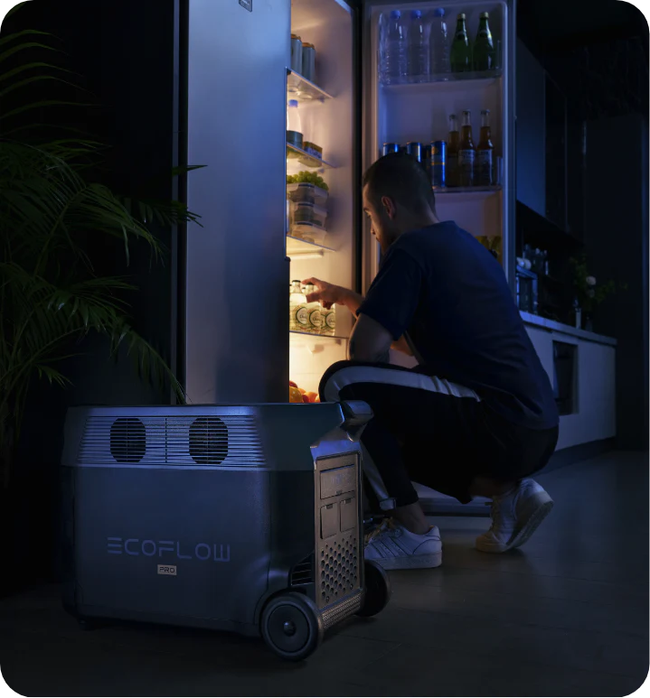An individual crouched to look inside a refrigerator, which is powered by an EcoFlow DELTA Pro. 