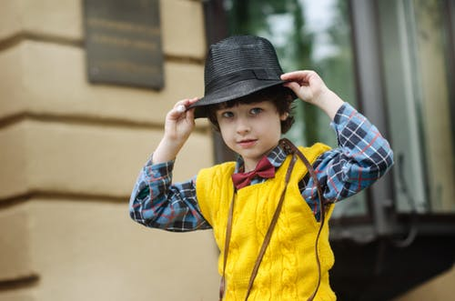 a boy wearing a yellow vest and a black hat