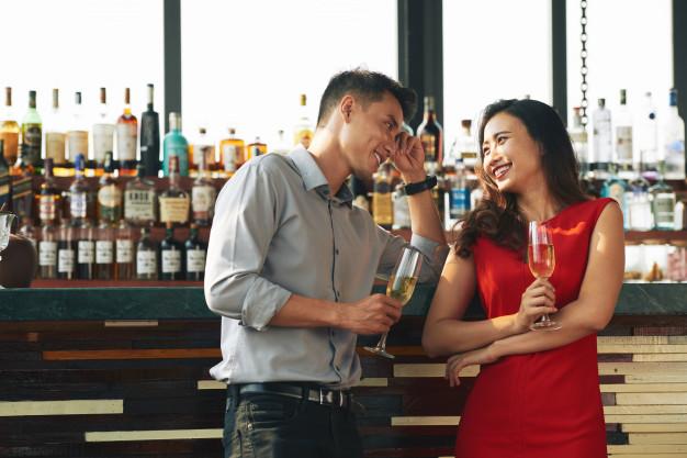 Tiro médio de dois estranhos flertando no bar bebendo champanhe Foto gratuita