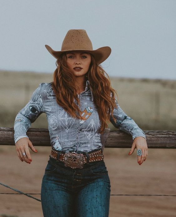 a cowgirl dressed in denim, a long-sleeved shirt, hat, and a belt