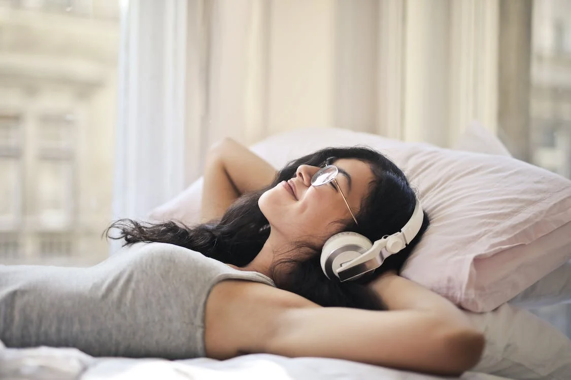 Woman lying on a bed with headphones
