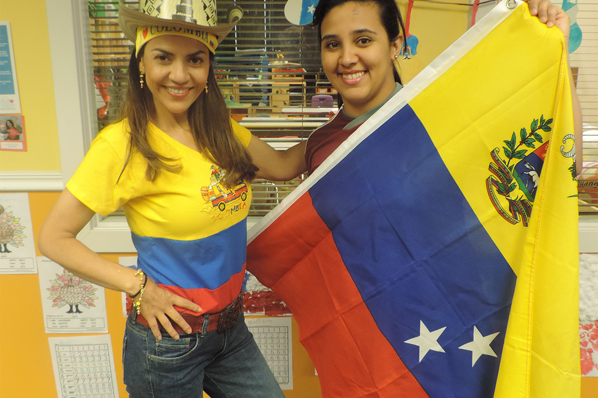 Casa teachers standing together with flag from Venezuela during Nationalities Day at our childcare center.