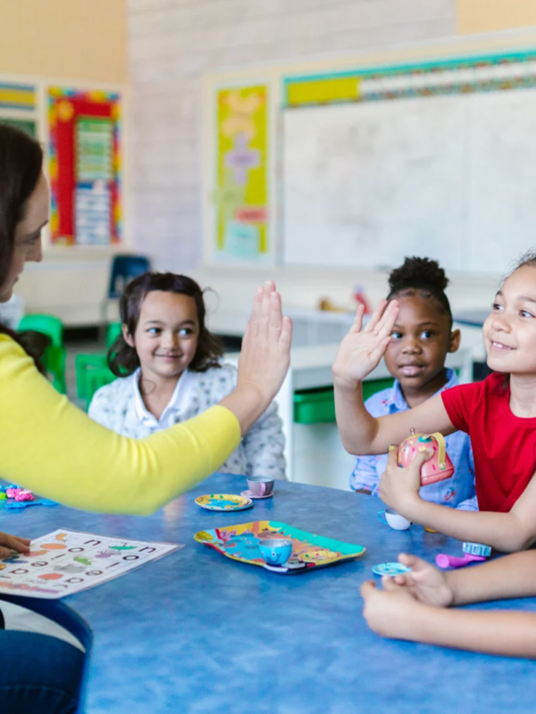 preschool teacher giving a high five to a young girl