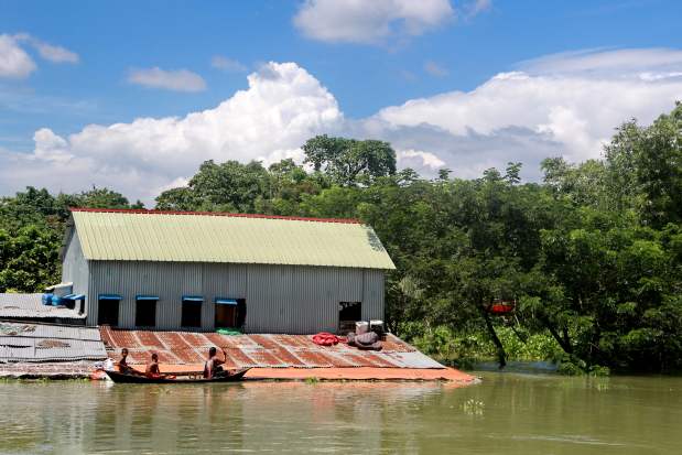 South Asia Floods: Children on a boat come to their two-storey tin-roofed house half of which is submerged in flood water, in Shibaloy, Manikganj district, Bangladesh. Credit: Farid Ahmed/IPS