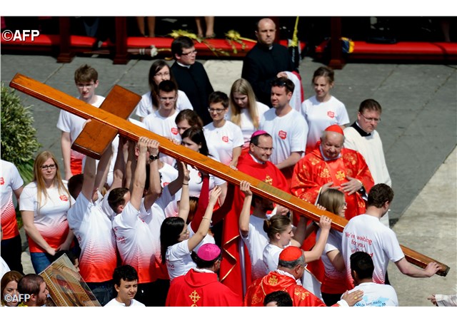 Young people from Poland carry the cross of the World Youth Day  next to the cardinal of Krakow Stanislaw Dziwisz (R) at St Peter's square during the Palm Sunday celebrations - AFP