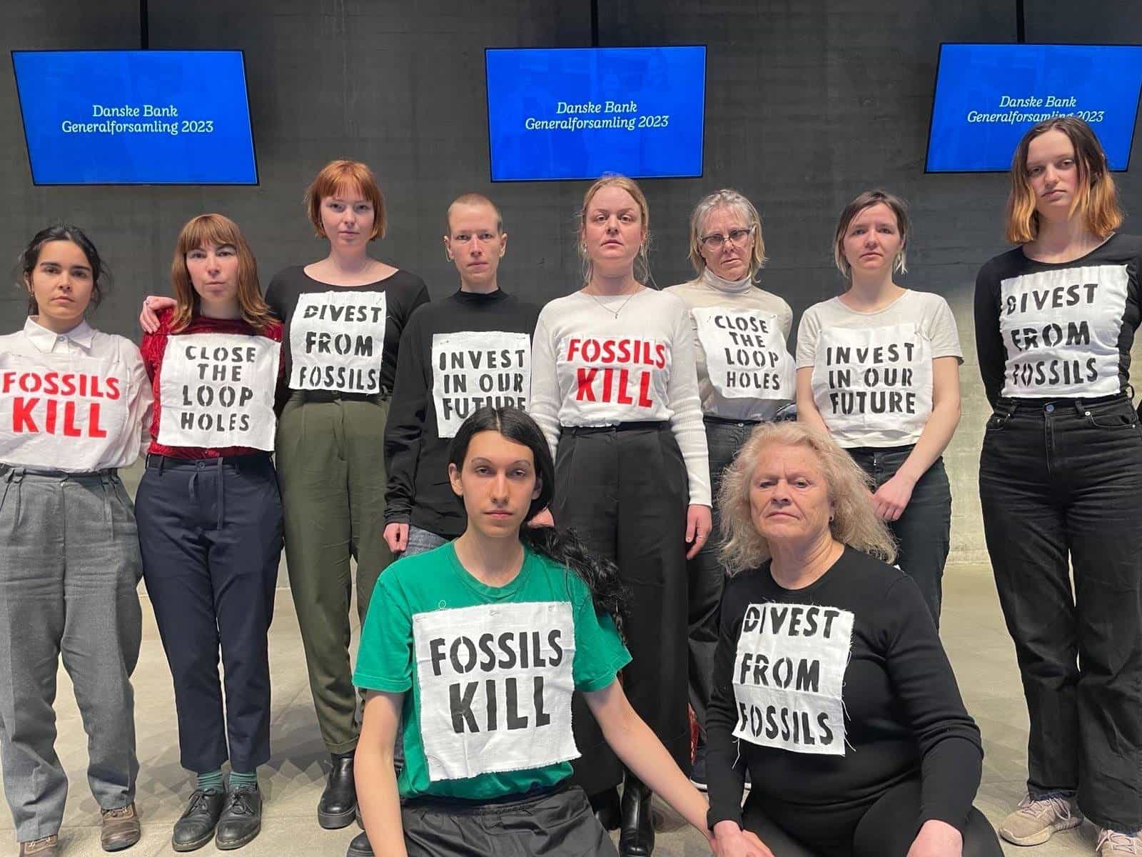 Members of scientist rebellion pose with climate crisis messages pinned to their shirts at a Danske Bank conference