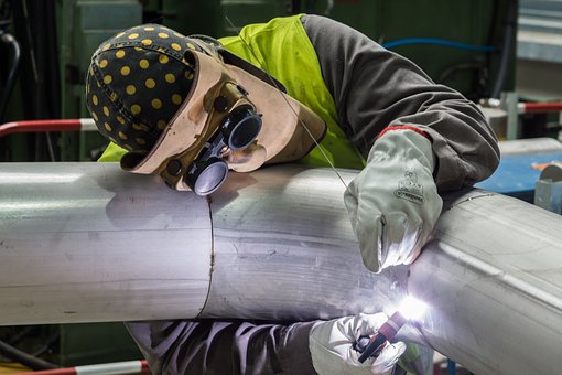 A welder works on a metal pipe