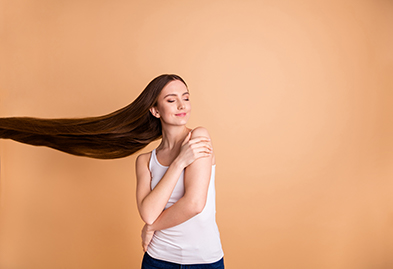 A woman with really long brown hair hugging herself