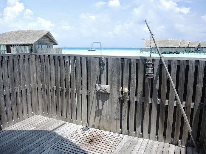 a shower outside with a wooden fence and a beach in the background