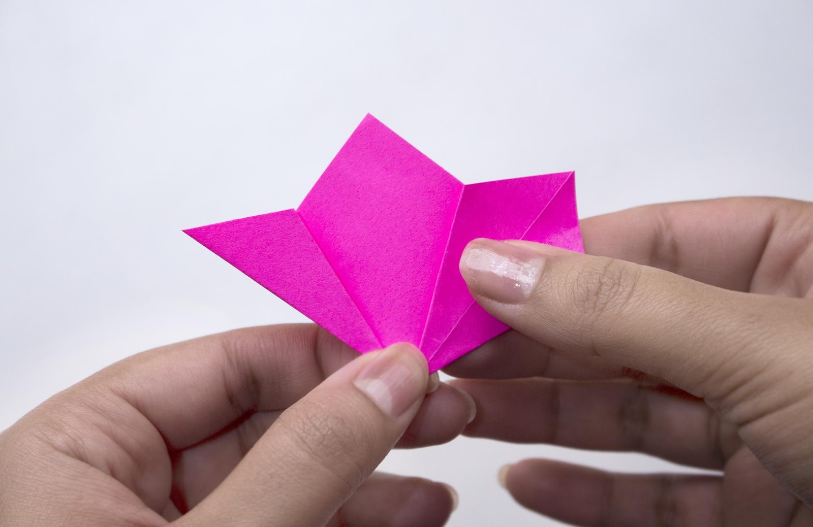 A sheet of pink  paper is being folded