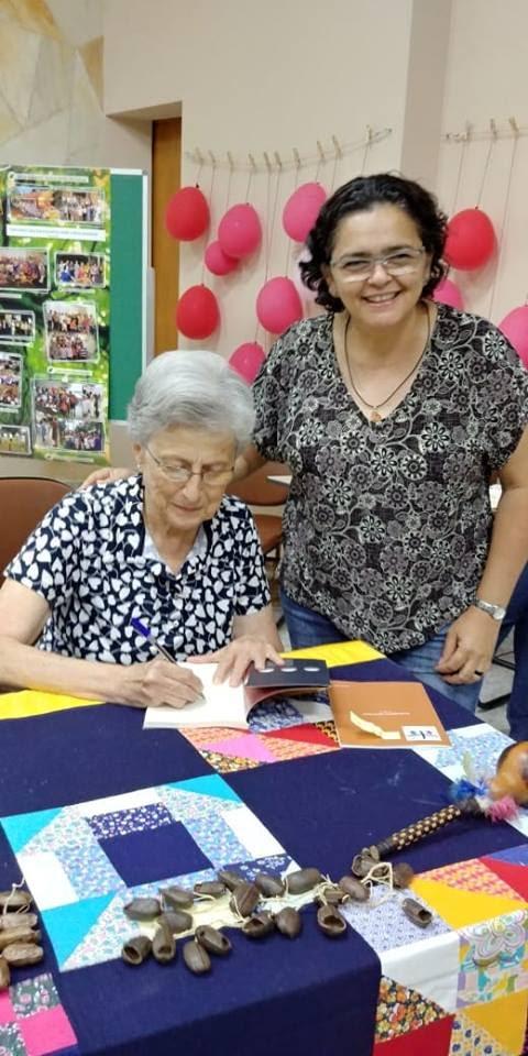 A imagem pode conter: 2 pessoas, pessoas sorrindo, pessoas sentadas e Ã¡rea interna