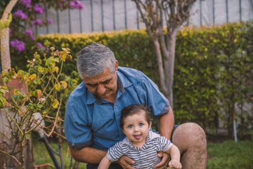 A grandfather holding his grandchild that he saved extra money for after reading a helpful Revolut review. 