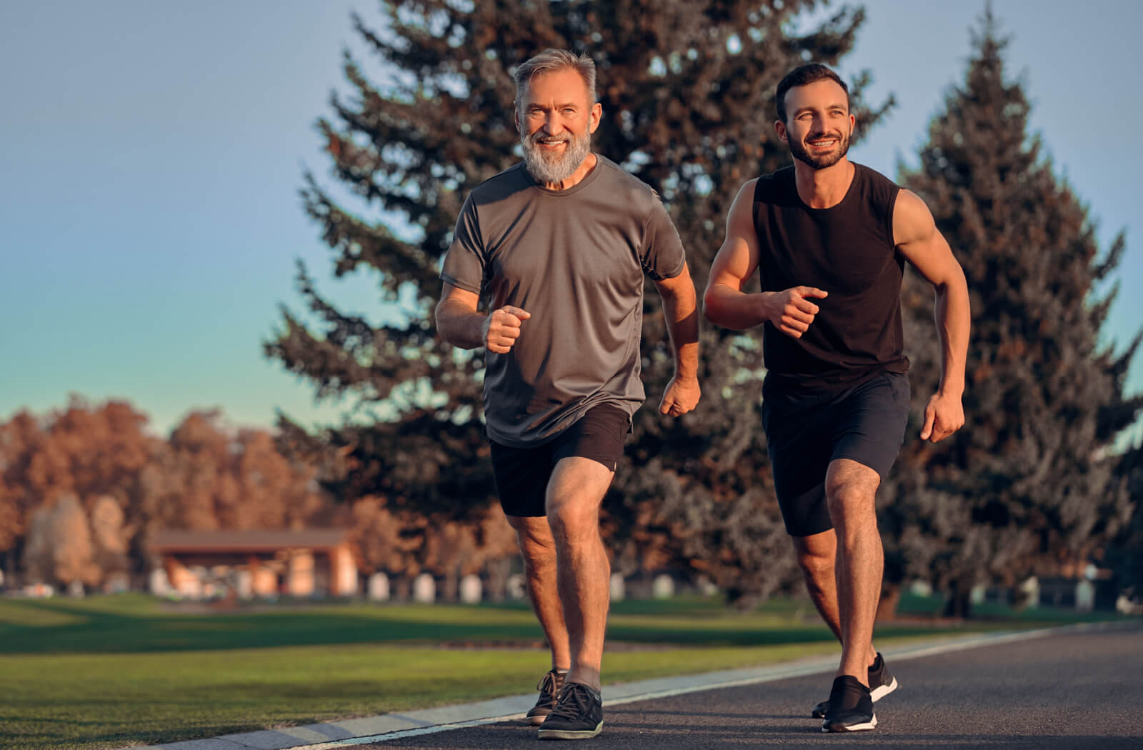 An energetic senior man having an early morning jog with his adult son.