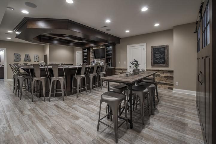 huge basement bar with dark wood furniture, metal chairs, barnwood floors and recessed lighting