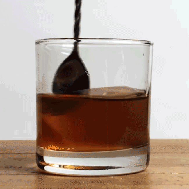 GIF of a bar spoon stirring a cocktail inside a rocks glass. 