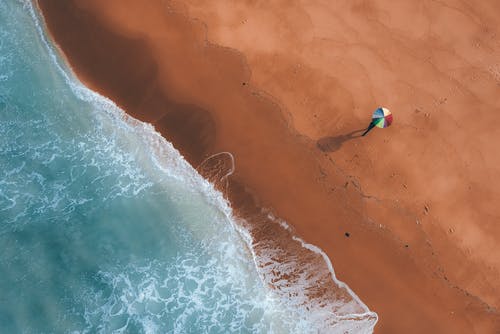 Sandy beach with colorful umbrella on sunny day