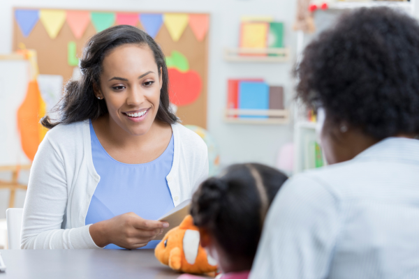 Teacher sitting at desk with parent and child.