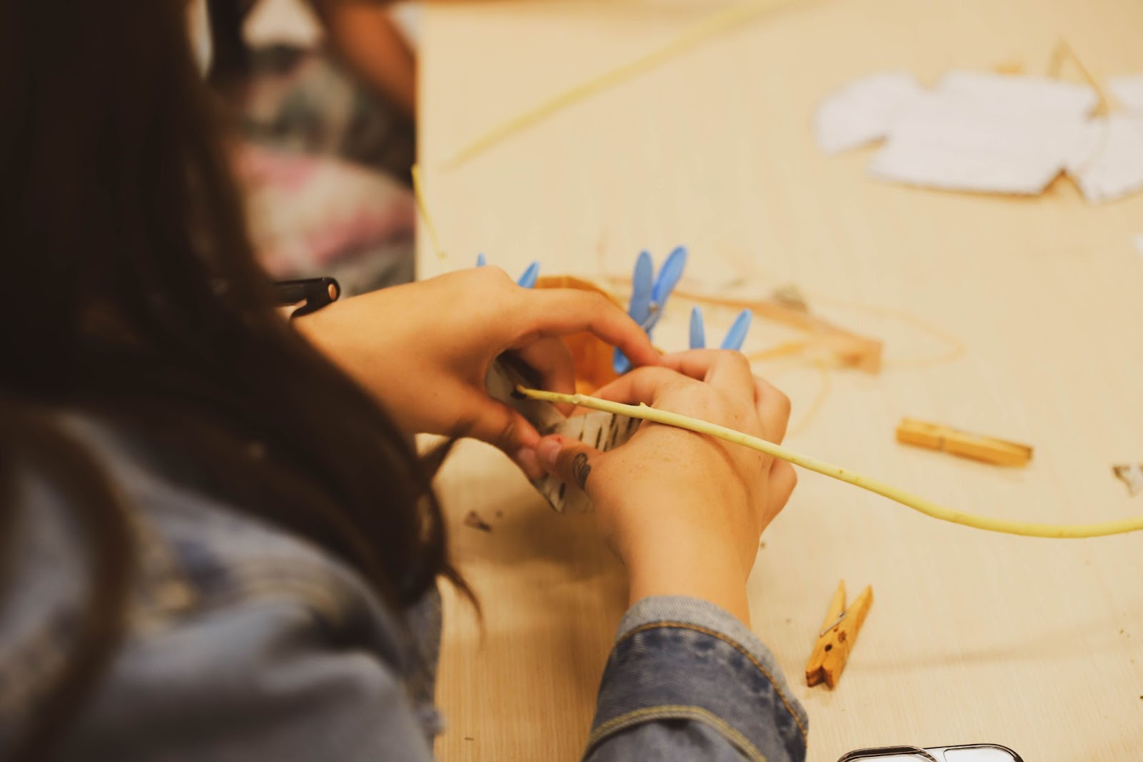 Woman weaving a birch bark basket using pliable willow twigs and securing them in place with clothespins