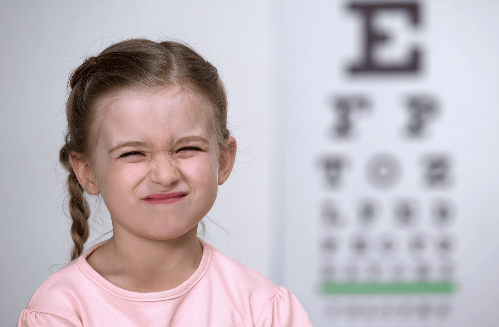 A young girl squinting due to difficulties seeing with myopia