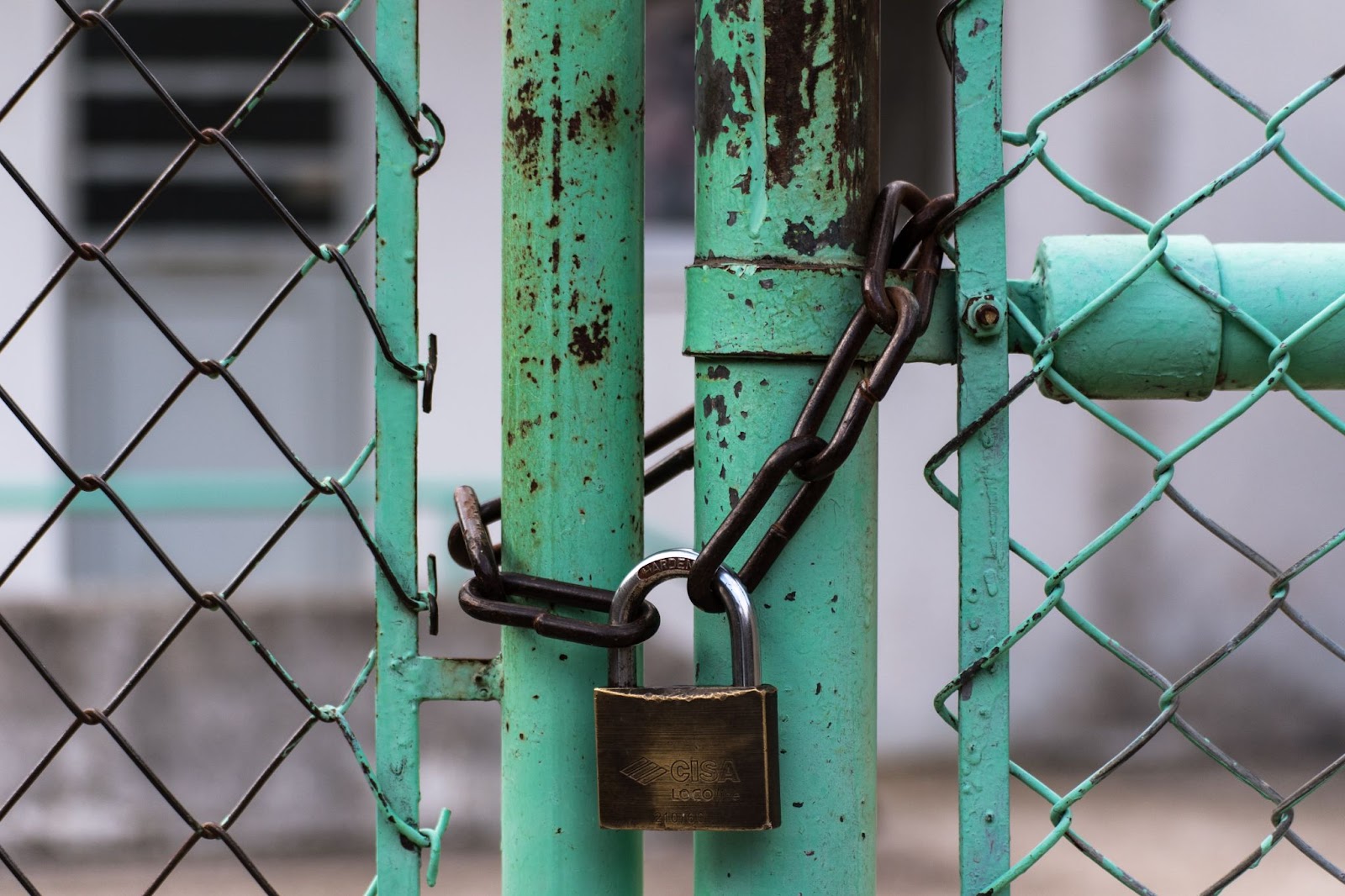 Alt Rusted green gate, chained and padlocked closed.