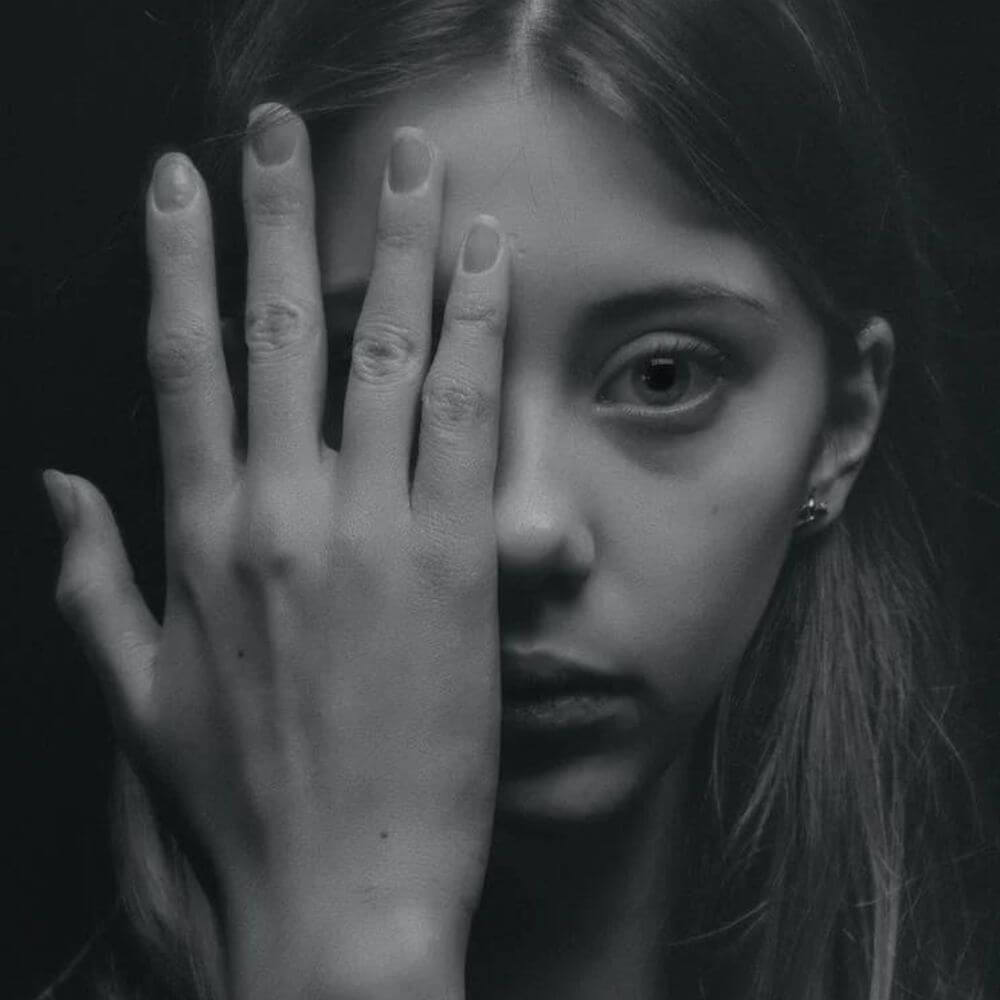 lady with hand over one side of her face looking at camera