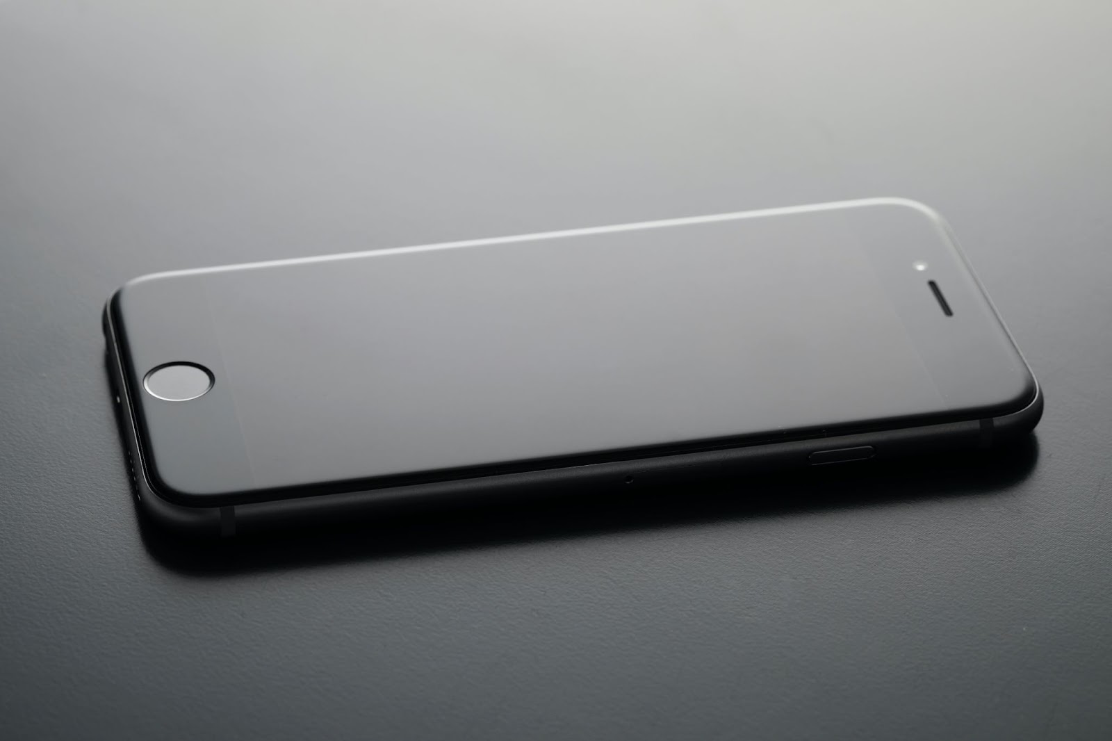 This image shows iPhone SE 2022 in black color and black background with slightly white light.