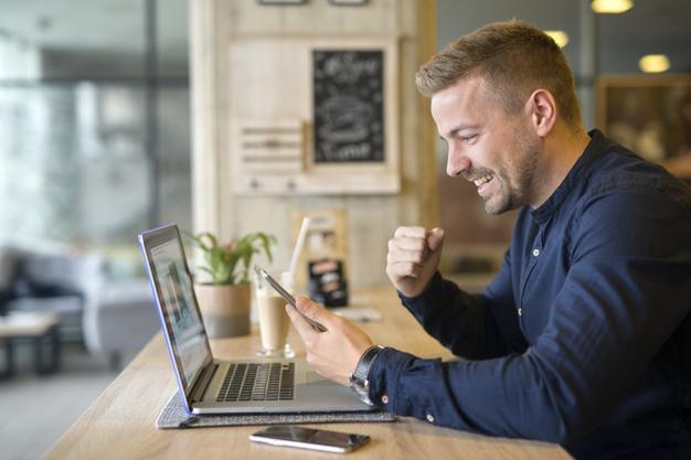 Happy freelancer with tablet and laptop computer in coffee shop Free Photo