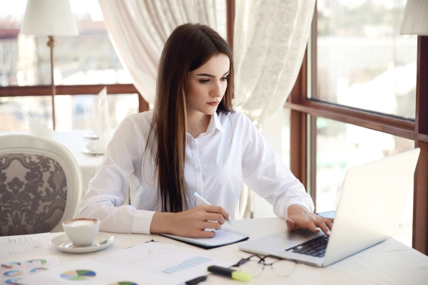 front-view-young-brunette-businesswoman-which-is-working-laptop-writing-something-down