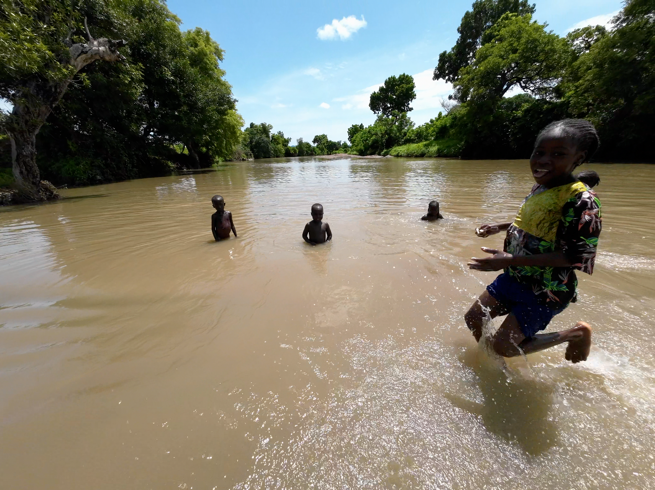 A group of children playing in a river

Description automatically generated