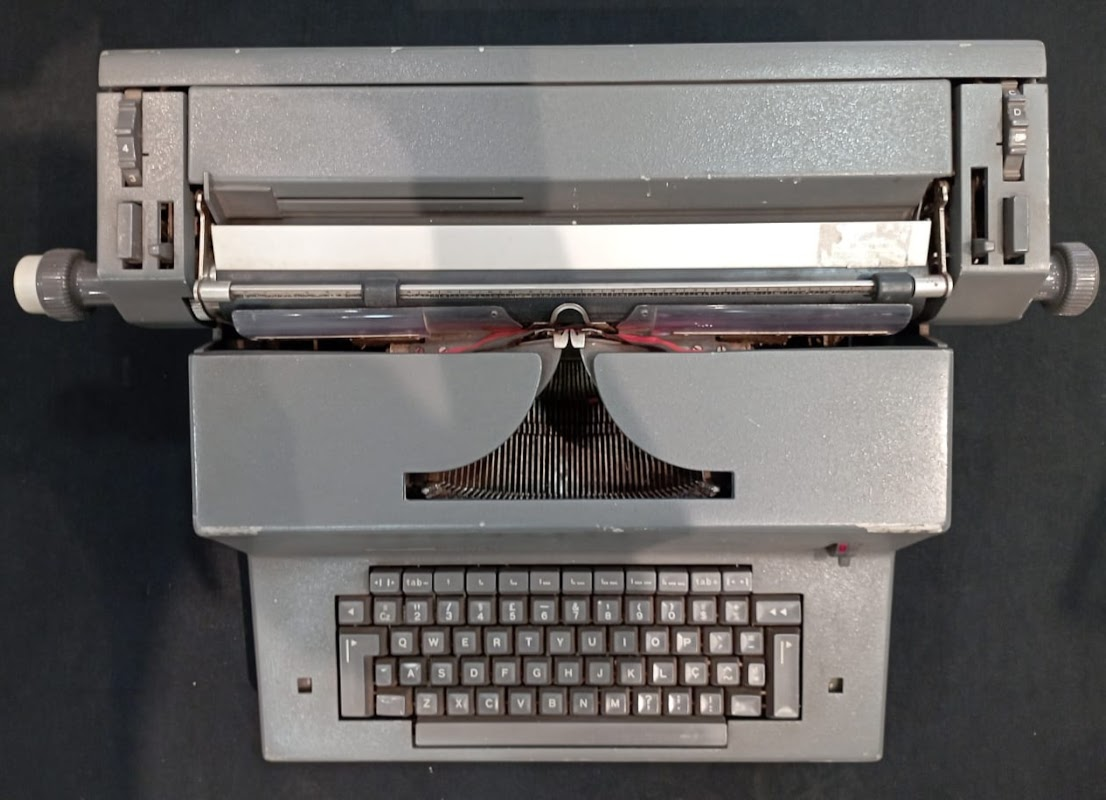 Máquina de escrever elétrica, modelo LINEA 98, marca Olivetti. Essa peça foi utilizada por diversas Diretorias, Gabinetes e Serviços do TRT da  24ª Região.