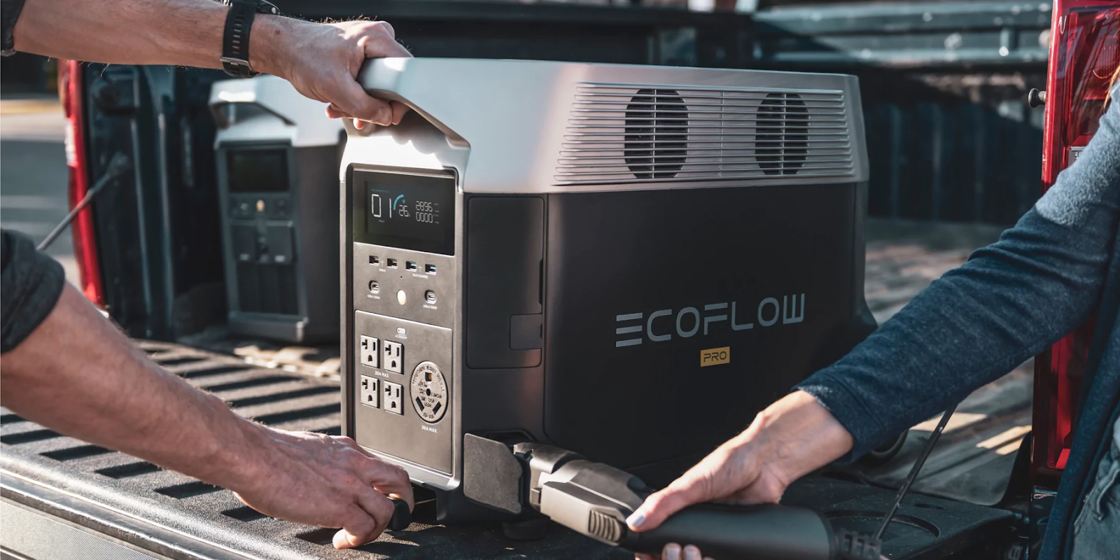 Two individuals loading an EcoFlow DELTA Pro onto a truck. 