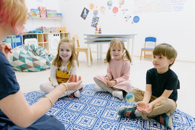 Three children sitting on a rug in a classroom at daycare