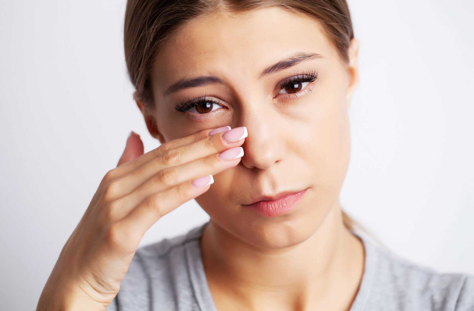 A woman experiencing moderate to severe eye pain due to not replacing expired contact lenses.