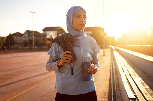 A young Muslim woman wearing a hijab and exercising, standing at the sidewalk holding her water bottle. Exercise can be one of the helpful coping skills to better manage your ADHD and anxiety. Feeling better and more hopeful is possible with help from an anxiety therapist in Woodland Hills, CA for anxiety treatment via online therapy in California. 91326 | 91303 | 91307 | 91377 | 91320 